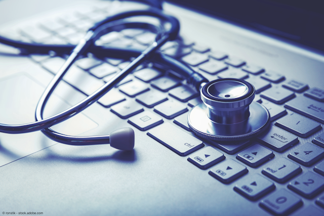 blue tinted photo of a stethoscope lying on a laptop keyboard 